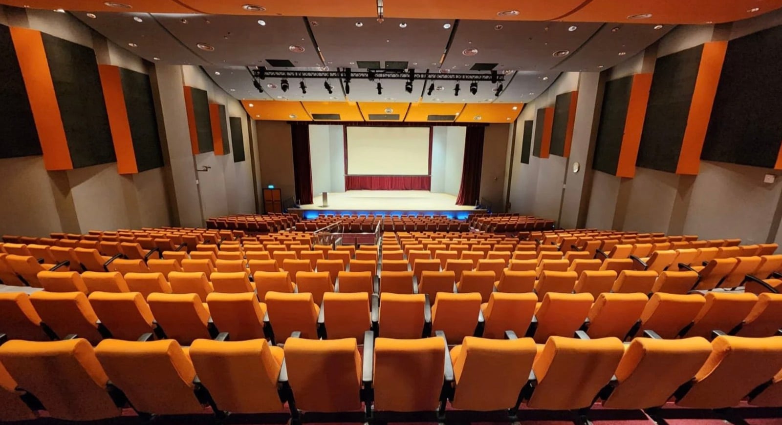 The Matrix auditorium, a tiered hall of orange seats facing a stage with a large projection screen